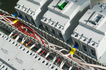 A series of modular magnetic contactors and a range of power circuit breakers. Between the rows of contactors and switches, perforated cable channels. To the contactor of the connected wires.