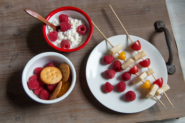 Snack idea, crackers, cheese, tomatoes, mandarin in enameled bowls 
