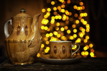 Teapot with corresponding teacup and a Christmas tree background