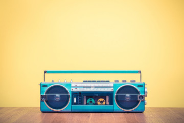 Retro outdated portable stereo mint green radio cassette recorder from 80s front yellow background....