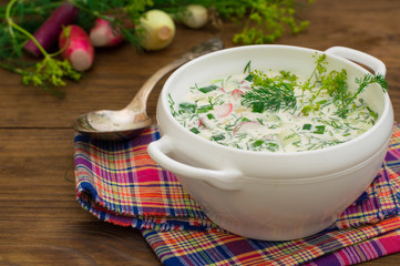 Okroshka. Summer light cold yogurt soup with cucumber, radish, eggs and dill on a wooden table. Wooden background. Close-up. Top view