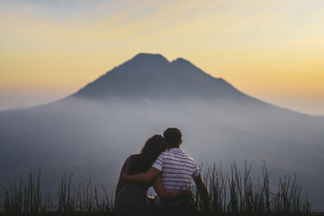 young couple watching sunrise in mountains