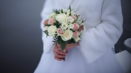 bride with flowers in hand outdoors. The bride is nervous before the wedding. Bride holding a perfume. nice wedding bouquet in bride's hand. Bride is holding beautiful bright wedding bouquet. the