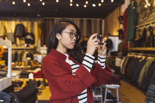 Stylish woman taking pictures with her phone in local downtown shop