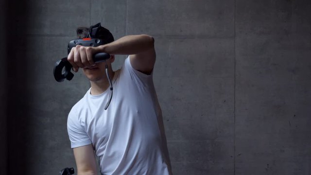 A man playing a driving simulation on a virtual reality headset. Medium shot.