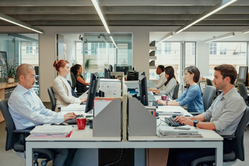 Rows of business people working at computers in stylish modern office