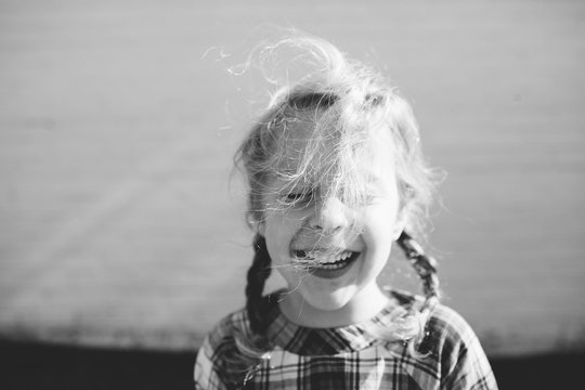 portrait of a little girl with a big smile as her hair blows in the wind