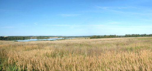 Panoramic view of countryside landscape with hills, lake, a village and christian church far away...