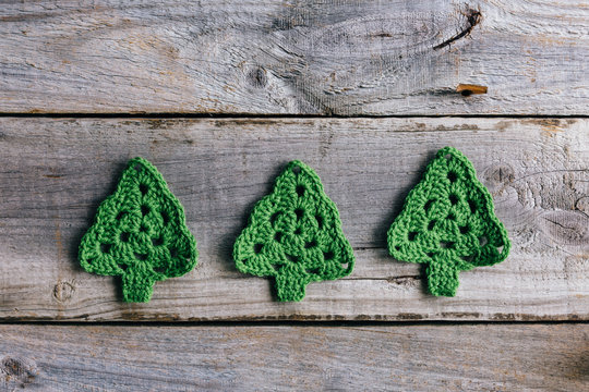 Three little crocheted Christmas trees on rustic wood background