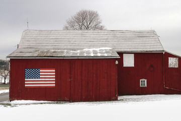 American Flag on rural barn in snowy landscape