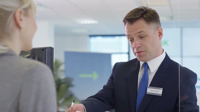  Modern city bank with friendly adviser talking to customer.