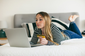Woman shopping online with her credit card from home.
