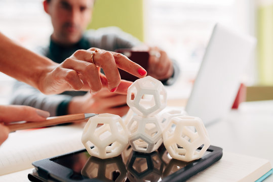 Engineering and design group of men and women take photograph of 3d printed hexagon design sample