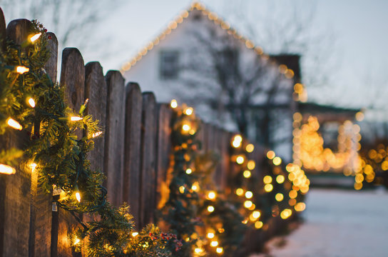 Holiday lights and garland adorn wooden fence
