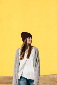 Caucasian woman walking in front of a yellow wall.