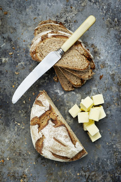 A loaf of rye bread cut into slices with butter cubes