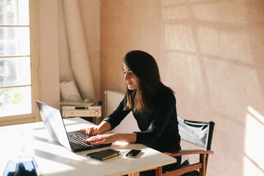 Beautiful brunette woman working on a laptop in her studio