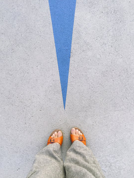 Looking down in a woman's feet wearing orange sandals