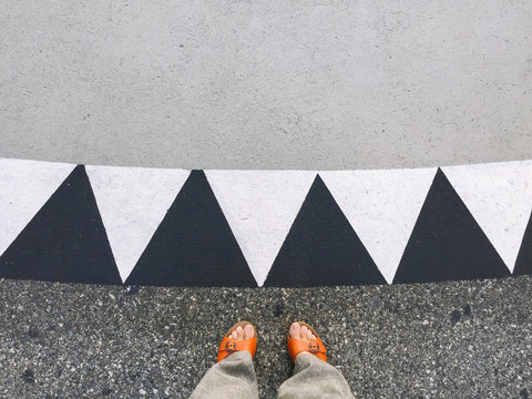 Looking down in a woman's feet wearing orange sandals