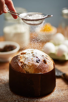 Man's hand powdering baked panettone with sugar