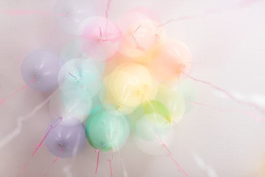 multiple exposure of pastel balloons against a white ceiling