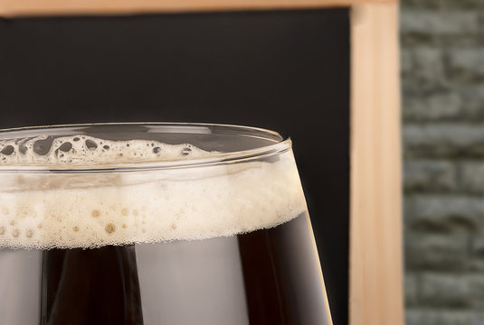 Close up on beer glass, blackboard menu in background.