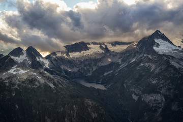 Aerial landscape view of Mount Tantalus and a Glacier Lake. Picture taken near Squamish, BC, Canada, during a cloudy sunset.