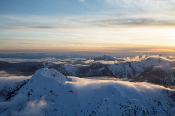 Beautiful Aerial Landscape View of the Mountain Range covered in Clouds during Sunset. Picture taken North of Vancouver, British Columbia, Canada.