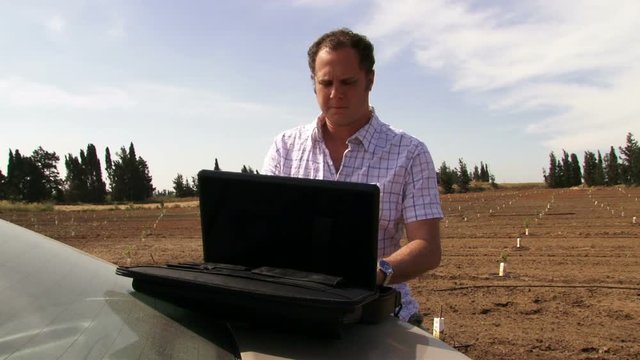 Guy working with laptop & typing on the field