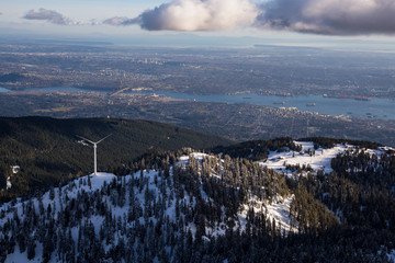Aerial view of Grouse Mountain and Vancouver Downtown City, BC, Canada, in the background. Picture taken during a cloudy winter sunset.
