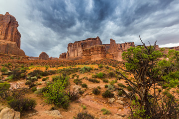 Fototapeta na wymiar Dramatic storm clouds, rain, and red sandstone formations in the Arches National Park, Utah