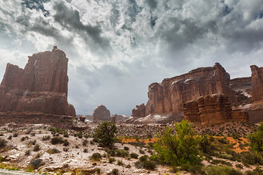 Dramatic storm clouds, rain, and red sandstone formations in the Arches National Park, Utah