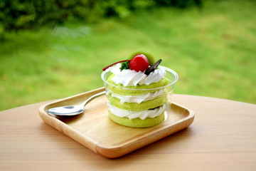 Three layer of green sofe cake with whipping cream and toping with chocolate cherry  and kiwi on...