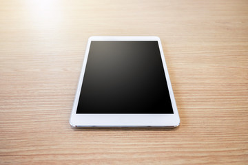 White digital tablet on wooden table background