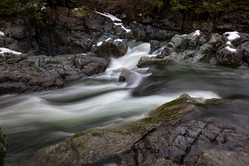 Nature view on the snow covered valley with the river flowing in between the rocks. Picture taken near Tofino, Vancouver Island, British Columbia, Canada.