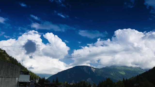 Timelapse: Blue sky and afternoon clouds shift to evening light over the town of Champex in the Alps along the Tour du Mont Blanc.