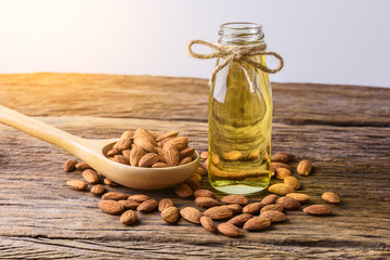Peeled almonds with bowl and Bottle of almond oil on rustic wooden