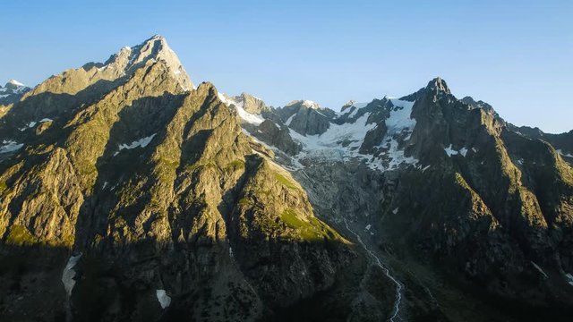 Timelapse: Bright morning sunrise on the mountains of the Alps across the valley from the Walter Bonatti Hut and refugio in Italy. Tour du Mont Blanc.