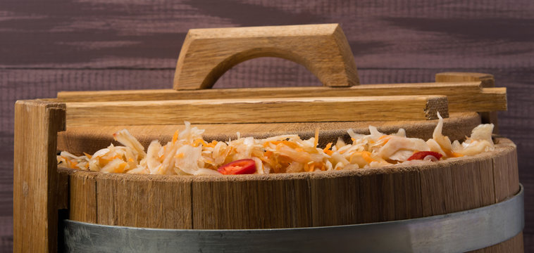 salad from cabbage and carrots, in a wooden storage tank, made of oak, covered with a lid