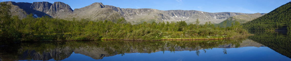 panorama with the mountains of the Khibiny, sky reflected in the lake Small Vudyavr. Kola Peninsula, Russia.