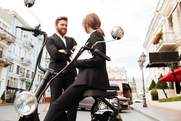 Happy business couple posing near the modern motorbike outdoors