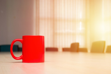Red mug on the table with a light leak
