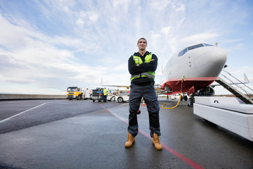 Confident Male Worker Standing Arms Crossed On Wet Runway