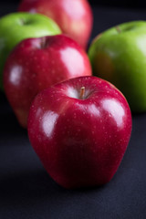 Green and red of apples on  black fabric background