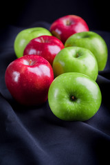 Green and red of apples on  black fabric background
