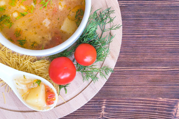 White soup noodles with tomatoes. Potatoes, dill, spices. On a wooden Board.