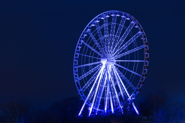 Night shot of a ferris wheel illuminated in blue