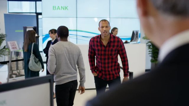  Worker at customer service desk assisting queue of customers in modern bank