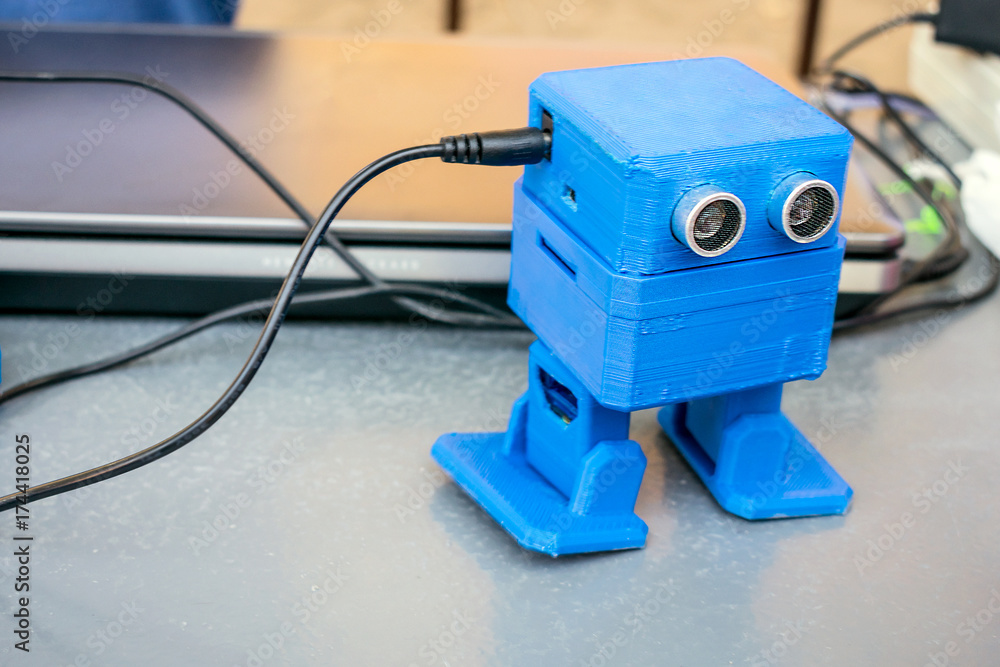 Poster funny blue robot printed on a 3d printer. toy cute automatic robots are dancing on the table. select