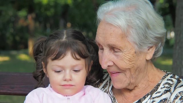 The face of an elderly woman and a child. Faces close-up of grandmother and granddaughter.